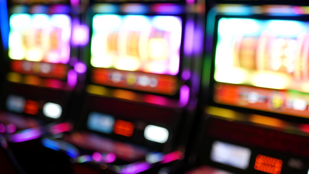Primer plano desenfocado de máquinas tragamonedas con luces de colores brillantes en un casino de Macao.