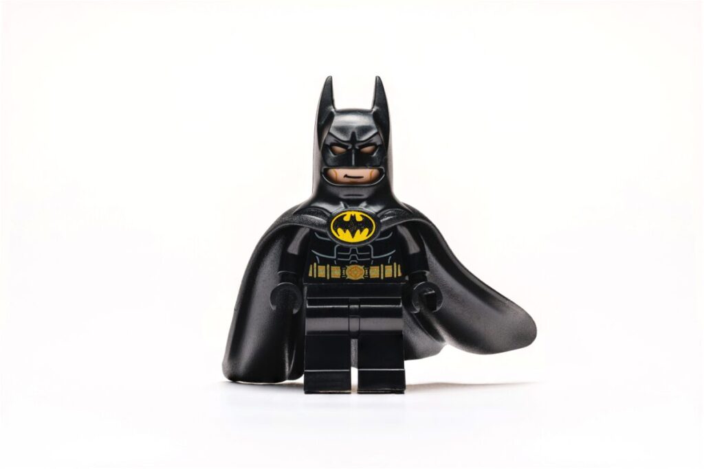 Figura LEGO de Batman con traje negro y logo amarillo, portada de artículo sobre Batman en LEGO y su nuevo videojuego 2026