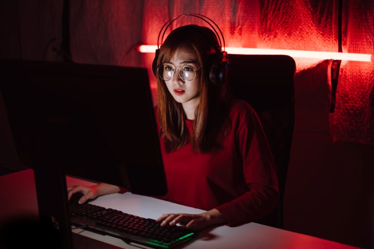 Joven gamer con auriculares y pantalla iluminada jugando en PC, reflejo del auge de Stellar Blade en la industria de videojuegos de Corea del Sur.